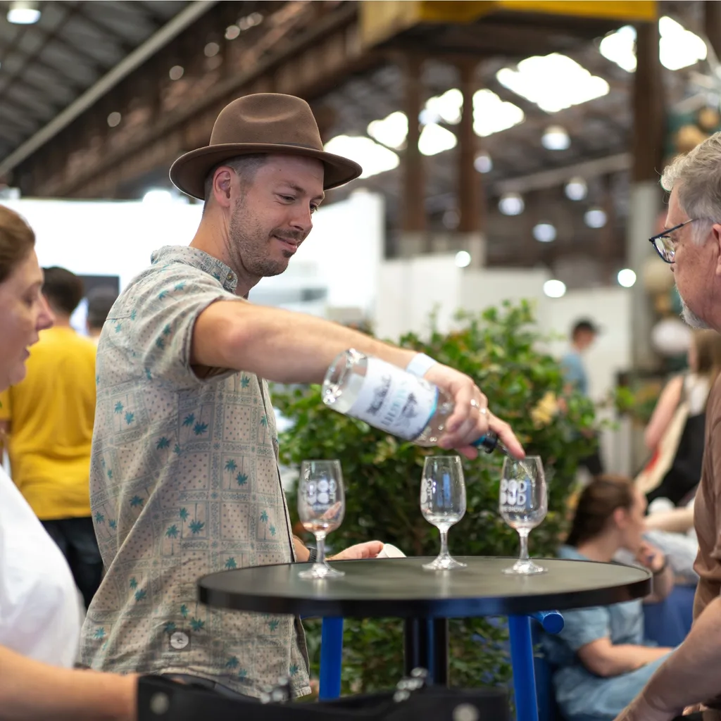 christmas markets sydney with man in hat pouring wine with christmas tree in background