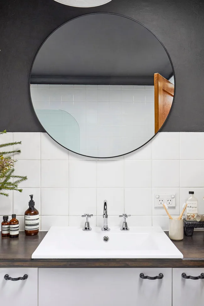 round mirror with black framing over bathroom sink