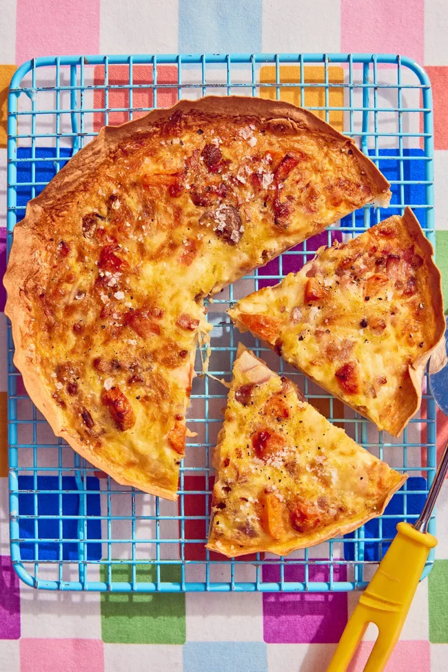 tortilla omelette with slice cut out of it on blue cooling tray