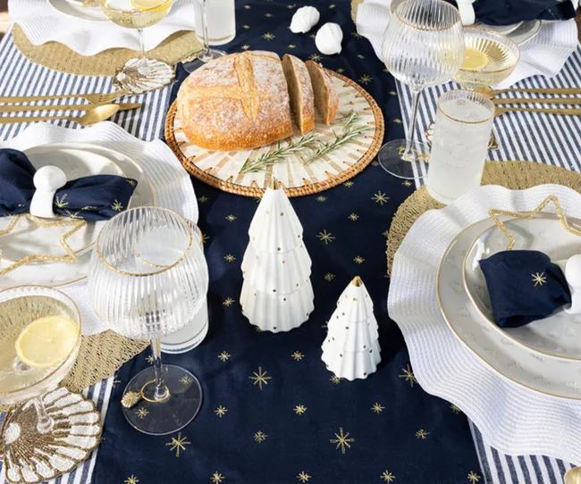 twinkle set from pillow talk with christmas table theme of stars with table runner in navy white plates and gold star shaped accents
