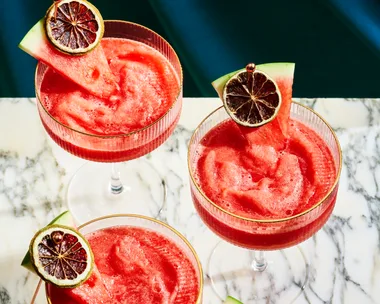 3 watermelon daiquiri's on a marble board, with a wedge of watermelon and a dried lime ontop of the cocktail as a garnish