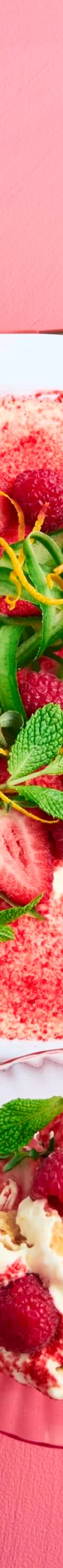 Tiramisu with a dusting of strawberries, with ribbons of cucumber and sprigs of mint on top in a square white baking dish sitting on a pink background
