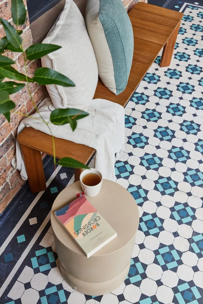 banco de madeira com almofadas e cobertor e piso frontal de concreto da varanda estampado com design de estilo da Federação azul e água com tinta.