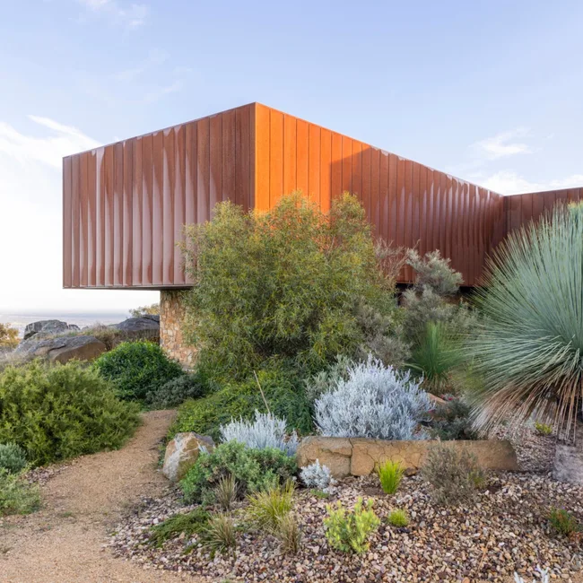 red corten steel building with organic garden in front