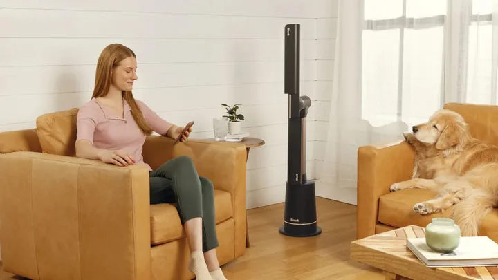 Woman sitting in an armchair with a charcoal Shark TurboBlade Ultra bladeless fan next to her chair