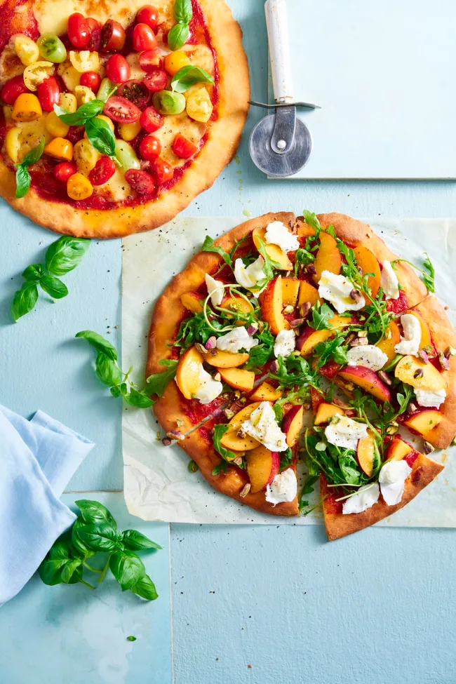 flatbread pizza with summer ingredients of peach tomato basil rocket
