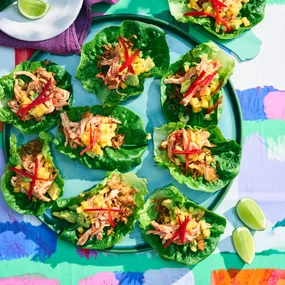 chicken lettuce cups with mango salsa on a green plate and colourful table cloth