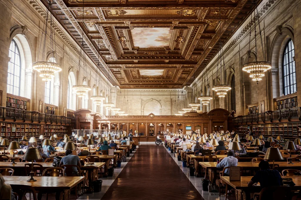 inside the new york library with people working at desks and gilded ceilings