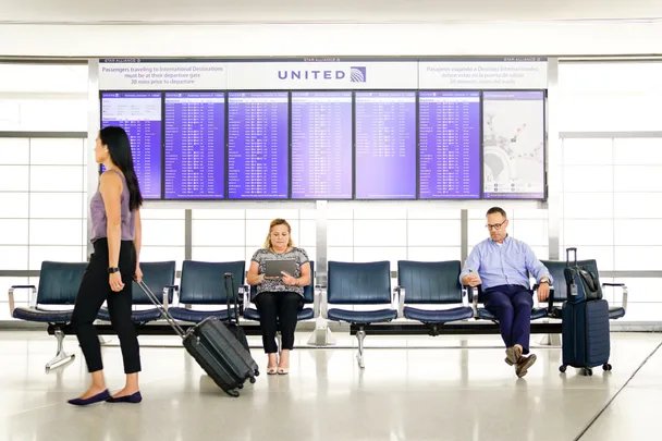 polaris business class image of timetable in purple and people with suitcases sitting in front