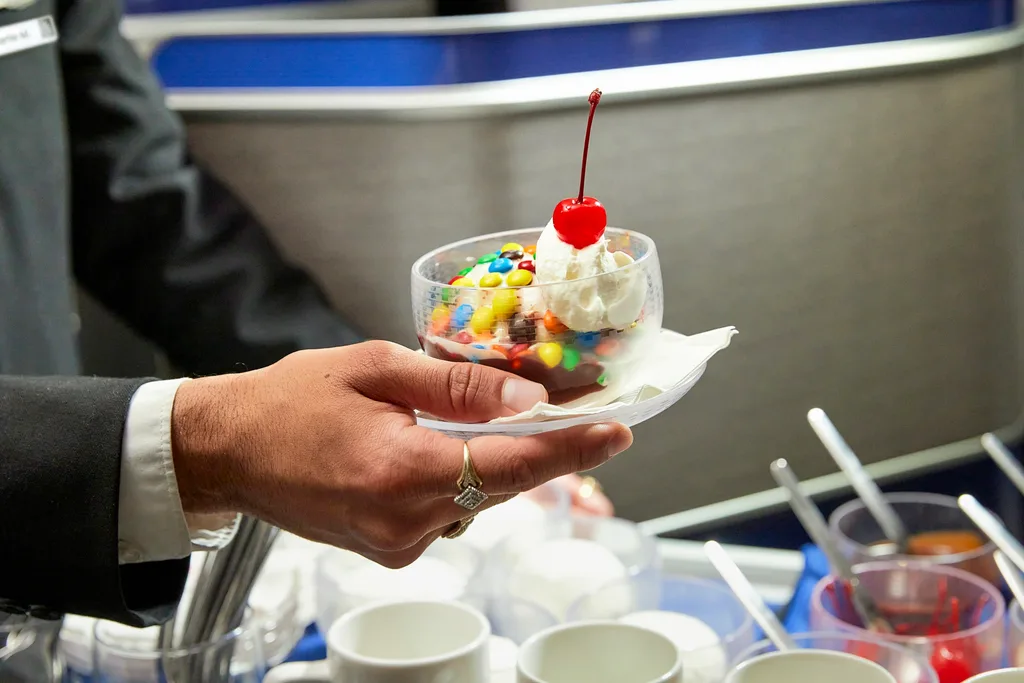 image of flight attendant holding out ice cream sundae with cherry on top and m &ms