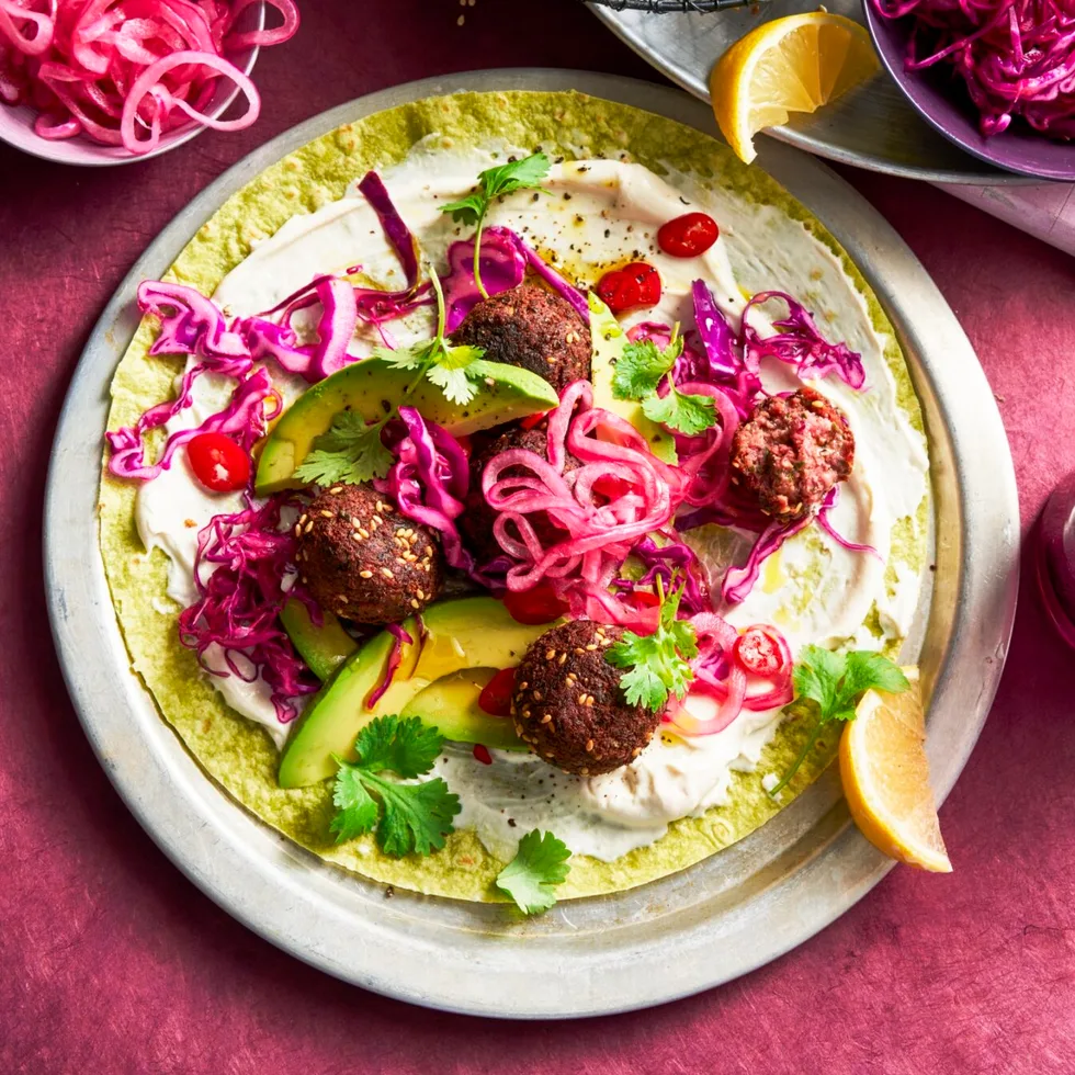 open wrap with purple pickled onion and beetroot on top of falafel