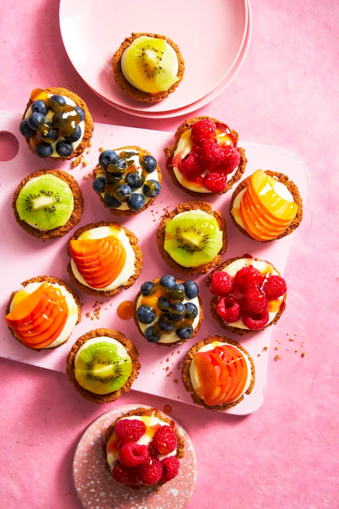 individual fruit tarts shot from birds eye view with blueberries, kiwi, peach and raspberries on them