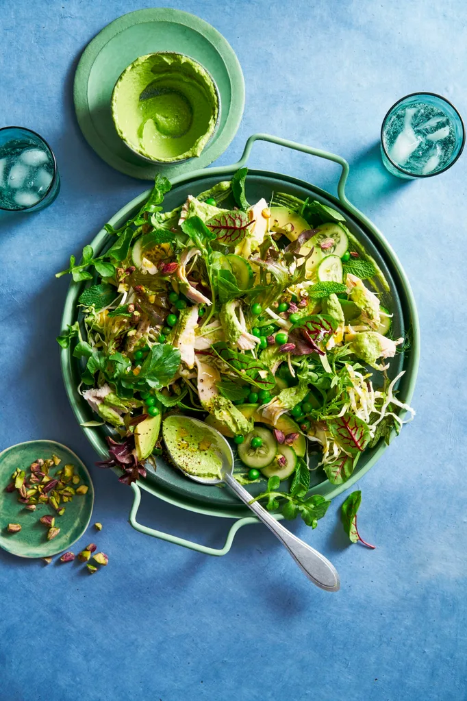 green salad with peas and salad with spoon sticking out and handle bowl