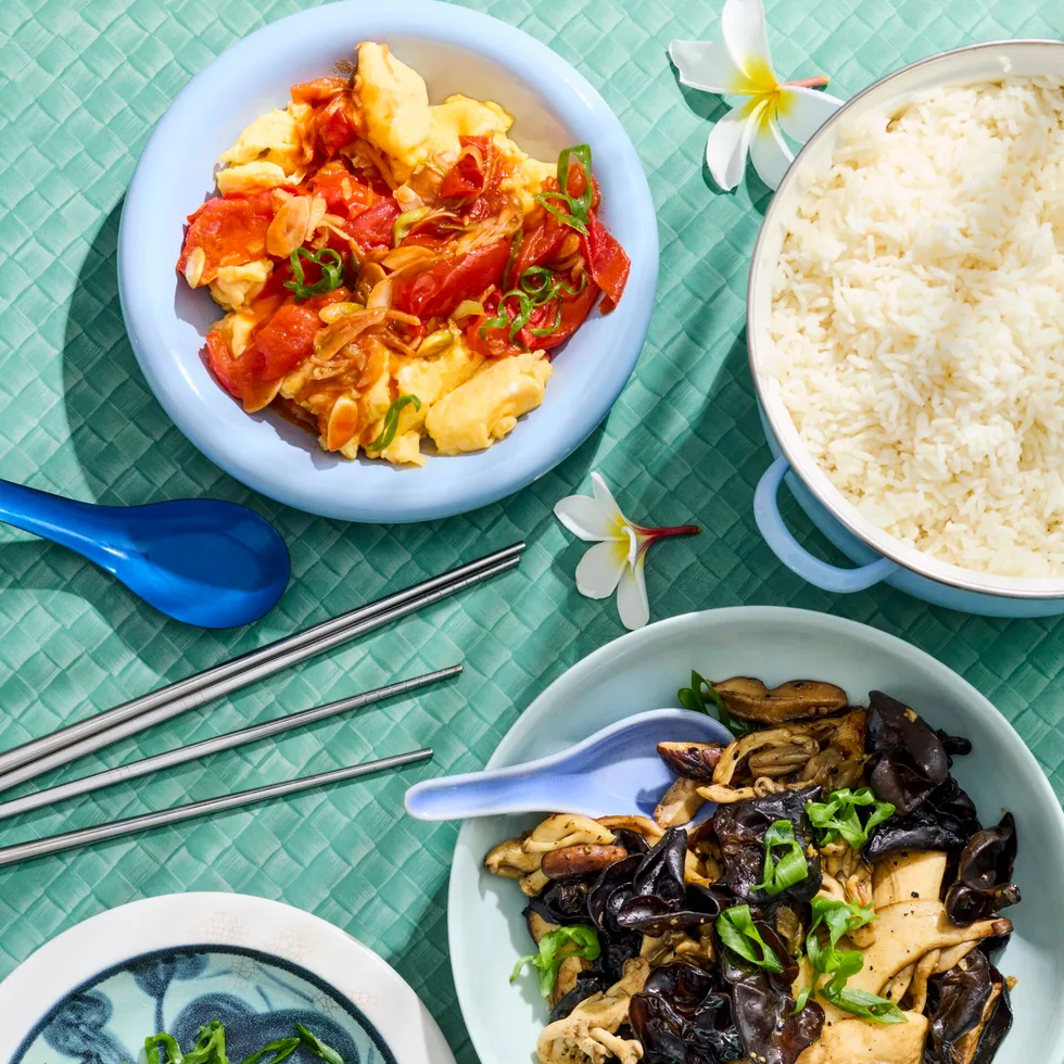 mushrooms in one bowl and tomato and egg stir fry in another bowl with greens on the side