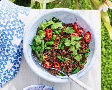 green beans with minced pork in a white bowl with grass background
