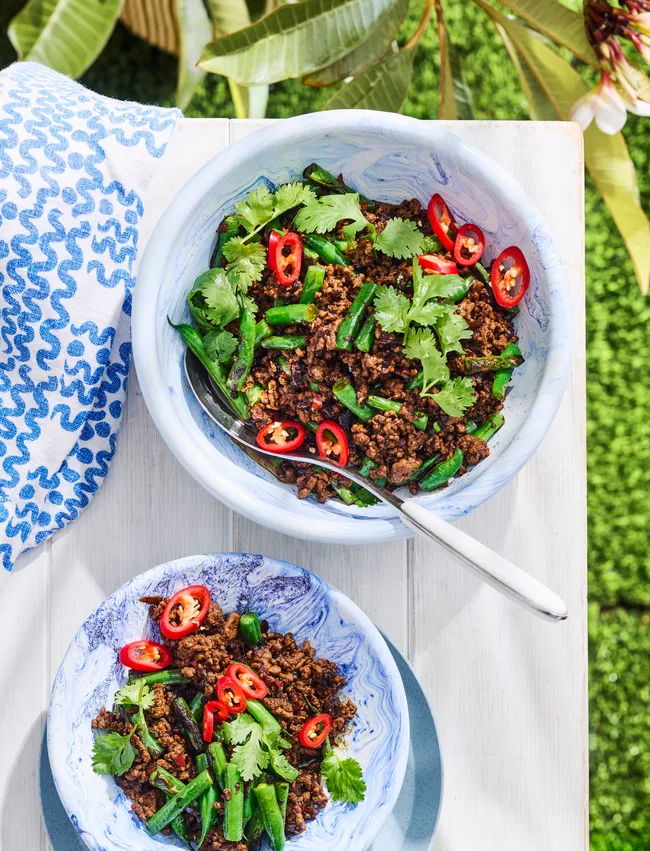 green beans with minced pork in a white bowl with grass background