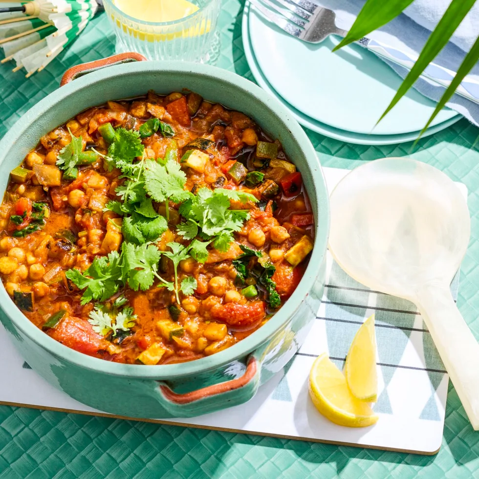 ratatouille in bowl with spoon on side and blue background