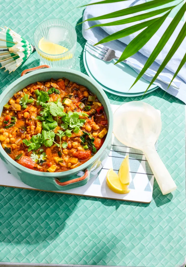 ratatouille in bowl with spoon on side and blue background