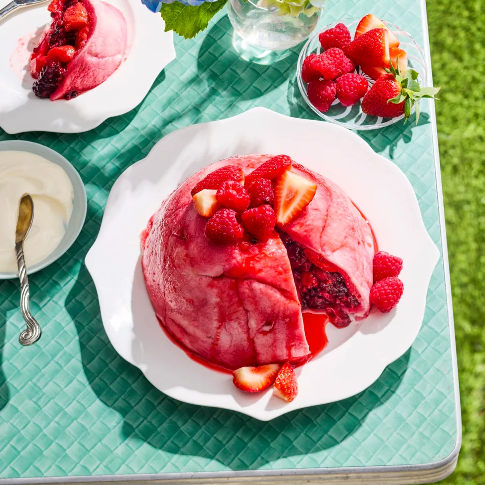 summer pudding bright pink colour on blue table with grass on the floor