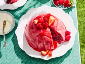 summer pudding bright pink colour on blue table with grass on the floor