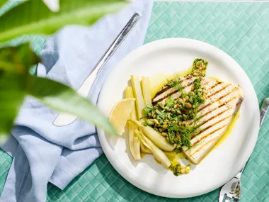 swordfish steaks with pickled fennel on white plate with blue tablecloth