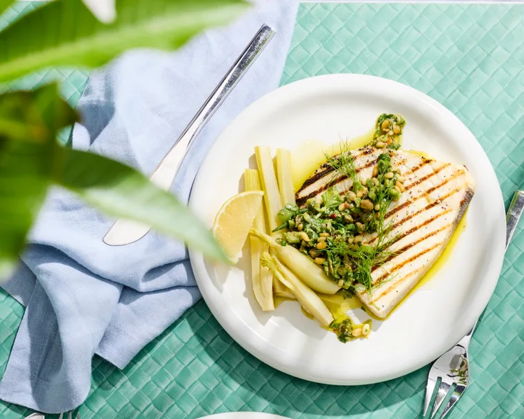 swordfish steaks with pickled fennel on white plate with blue tablecloth