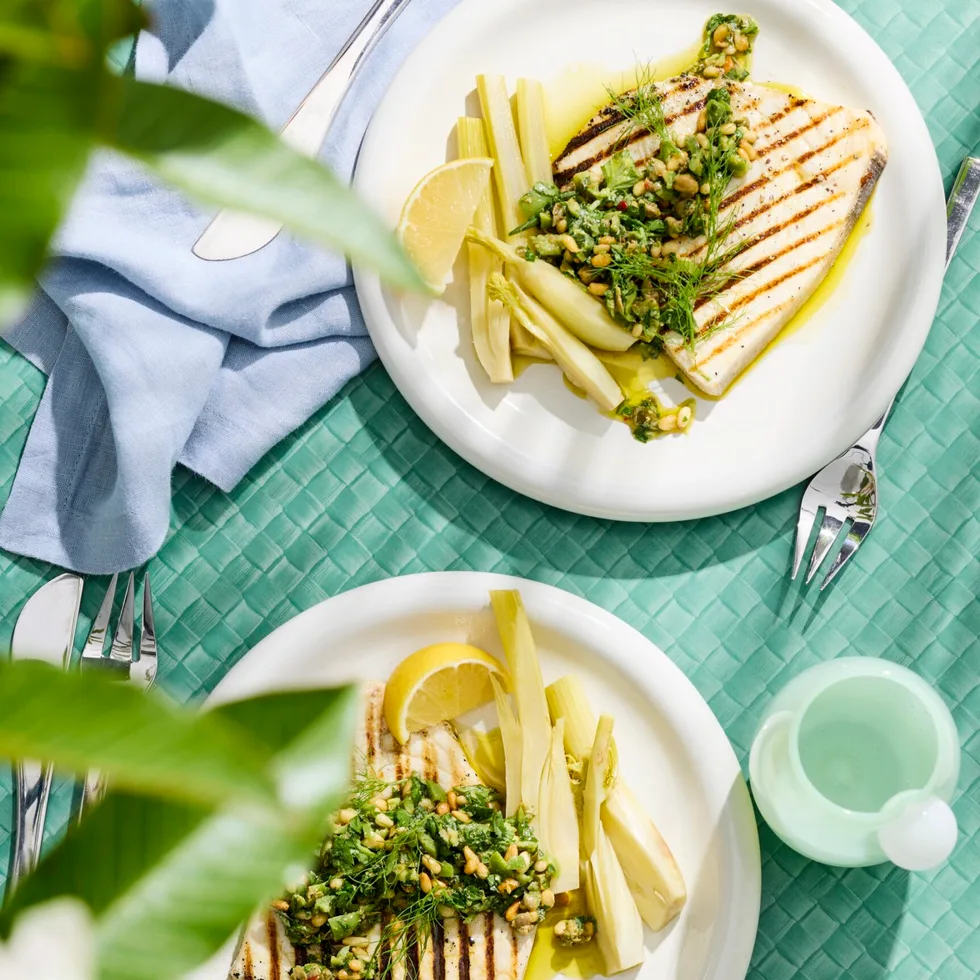 swordfish steaks with pickled fennel on white plate with blue tablecloth
