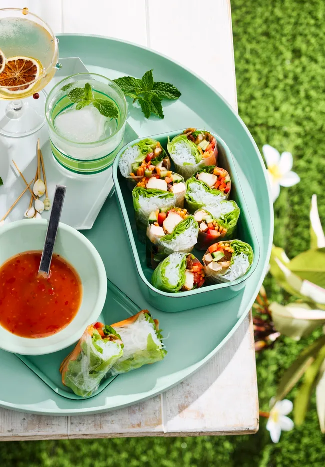chicken teriyaki rice paper rolls in lunchbox with bowl of sauce next to it