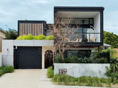 black square sustainable carbon neutral house with grass out the front and big concrete driveway