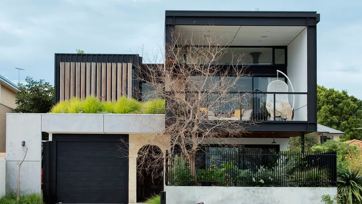 black square sustainable carbon neutral house with grass out the front and big concrete driveway