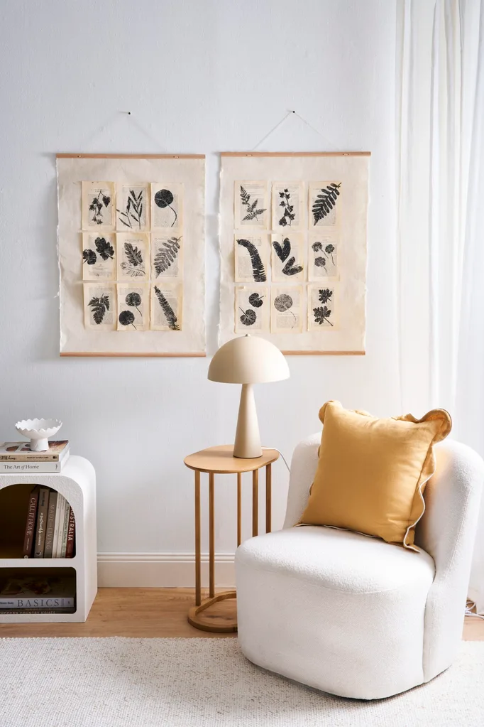 lounge chair with yellow cushion and leaf printing artwork on old book pages hanging on the wall