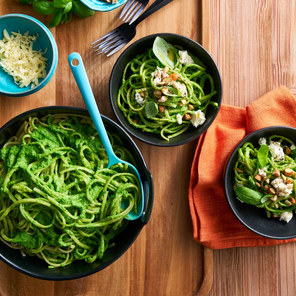 bright green pasta sauce with spaghetti in it in black bowls
