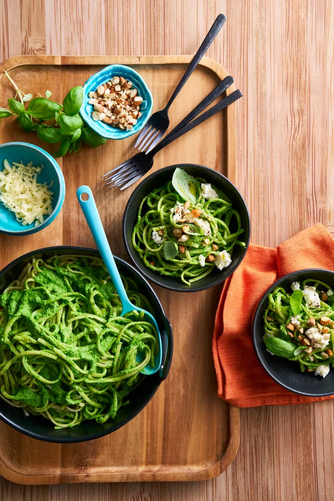 bright green pasta sauce with spaghetti in it in black bowls