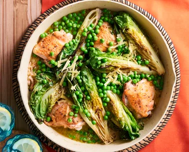 chicken peas bacon and charred lettuce in pan with sprinkle of herbs on top