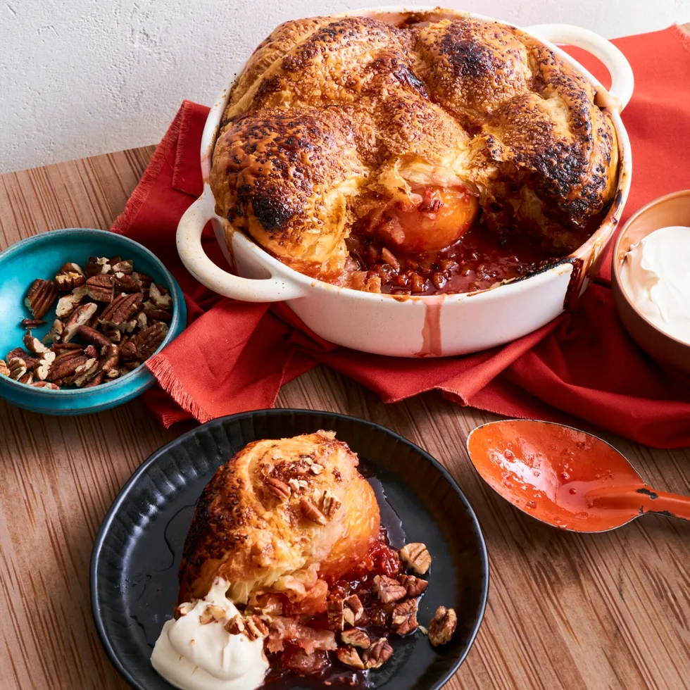 big peach and pecan pie in white dish with large mounds of pastry on top