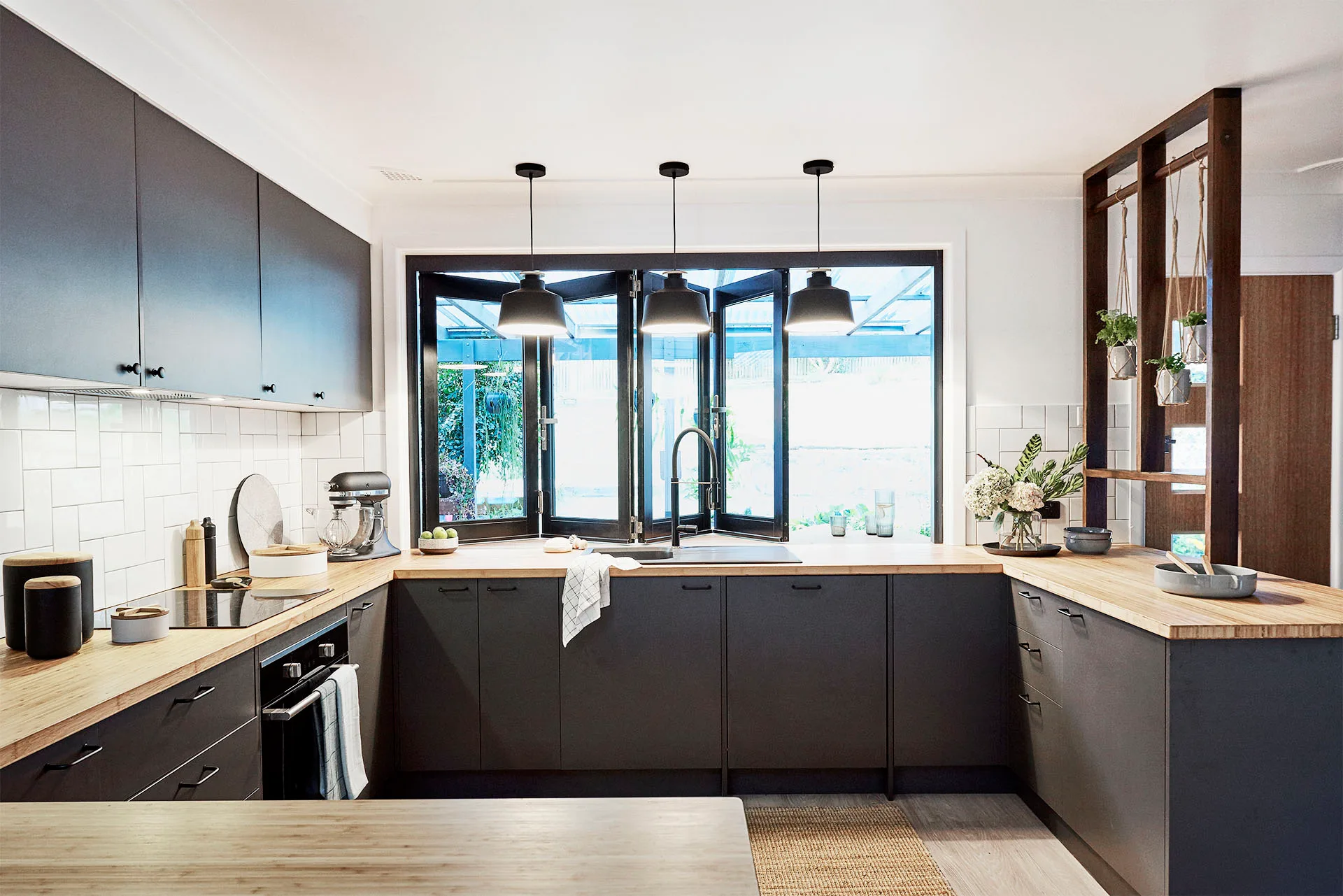 renovated modern kitchen with black cabinetry and bamboo bench tops