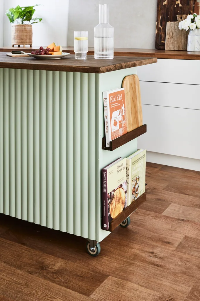 Ilha da cozinha verde na borda da prateleira de piso de madeira com livros de receitas