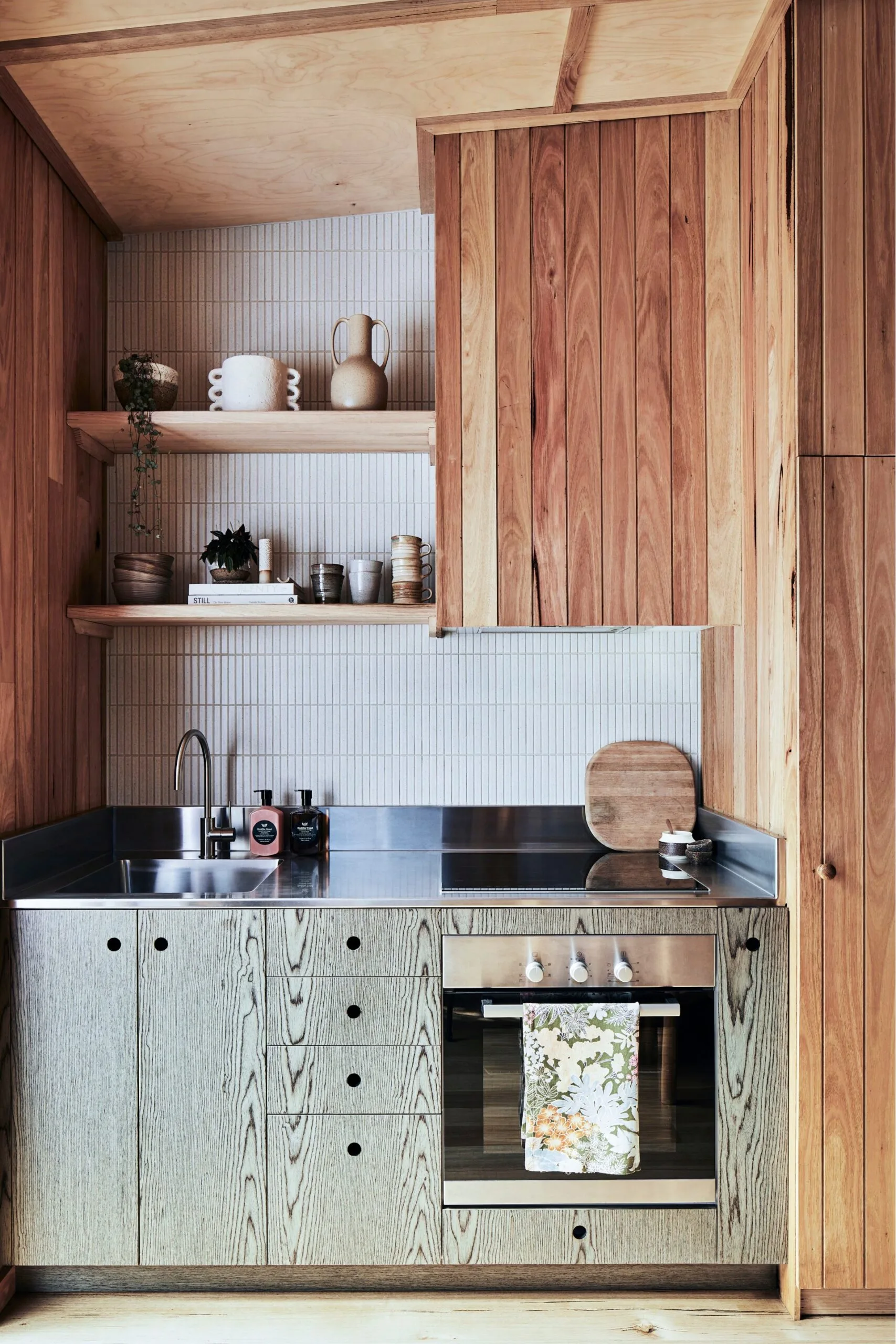 Small stainless steel and timber kitchen with white finger tiles