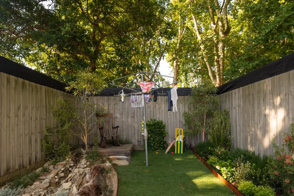 hills hoist on show lawn in aussie icons garden with backyard cricket set up next to native plant garden bed