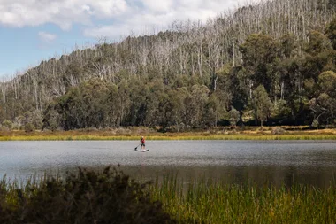 man paddle boarding on lake catani in victoria with orange life jacket on