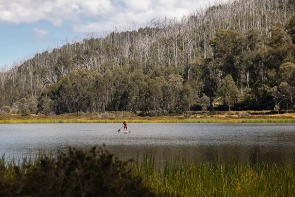 man paddle boarding on lake catani in victoria with orange life jacket on
