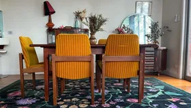 dining room table with wooden table, green ruggable rug and yellow chairs