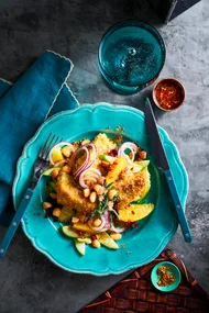 crumbed barramundi on blue plate with bush salad surrounding it
