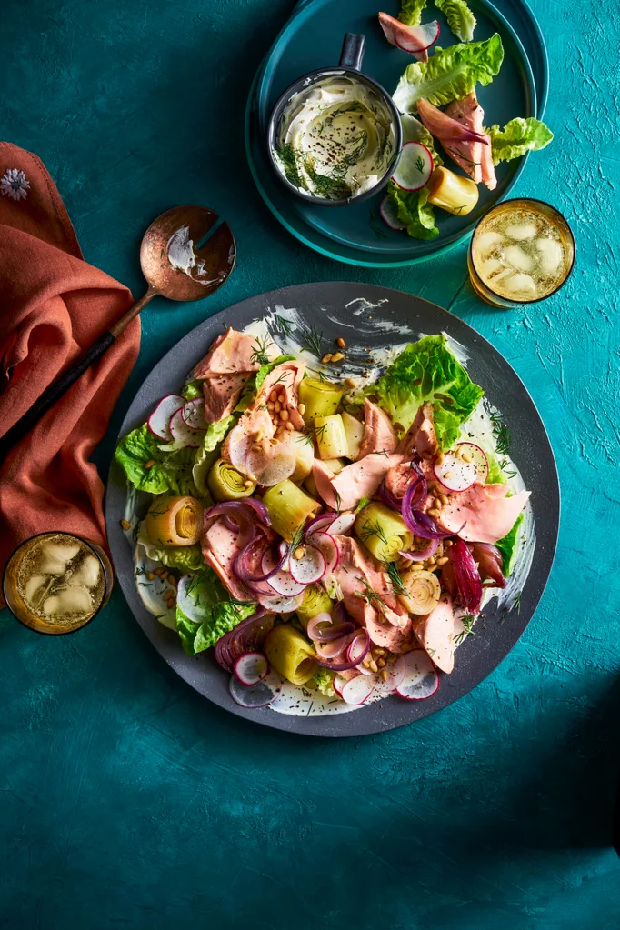 braised leeks poached trout salad in a black bowl on teal tablecloth
