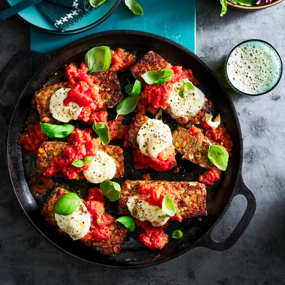 parmigiana meatloaf with basil on top in black casserole dish
