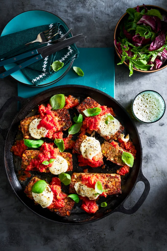 parmigiana meatloaf with basil on top in black casserole dish