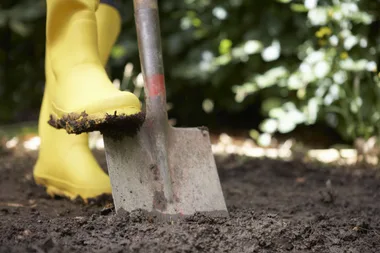gardening boots in bright yellow pushing down a shovel