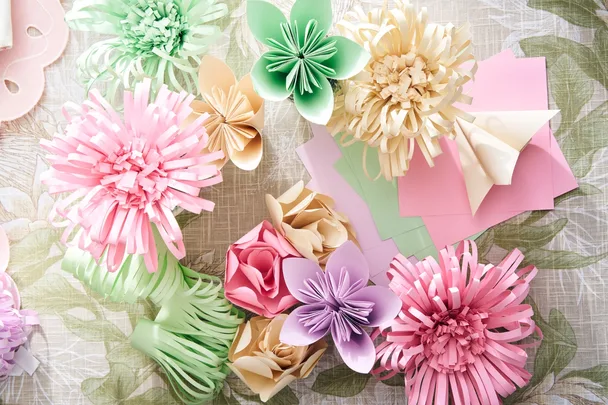 how to fold paper flowers with pink green and purple pastel folded flowers on craft table