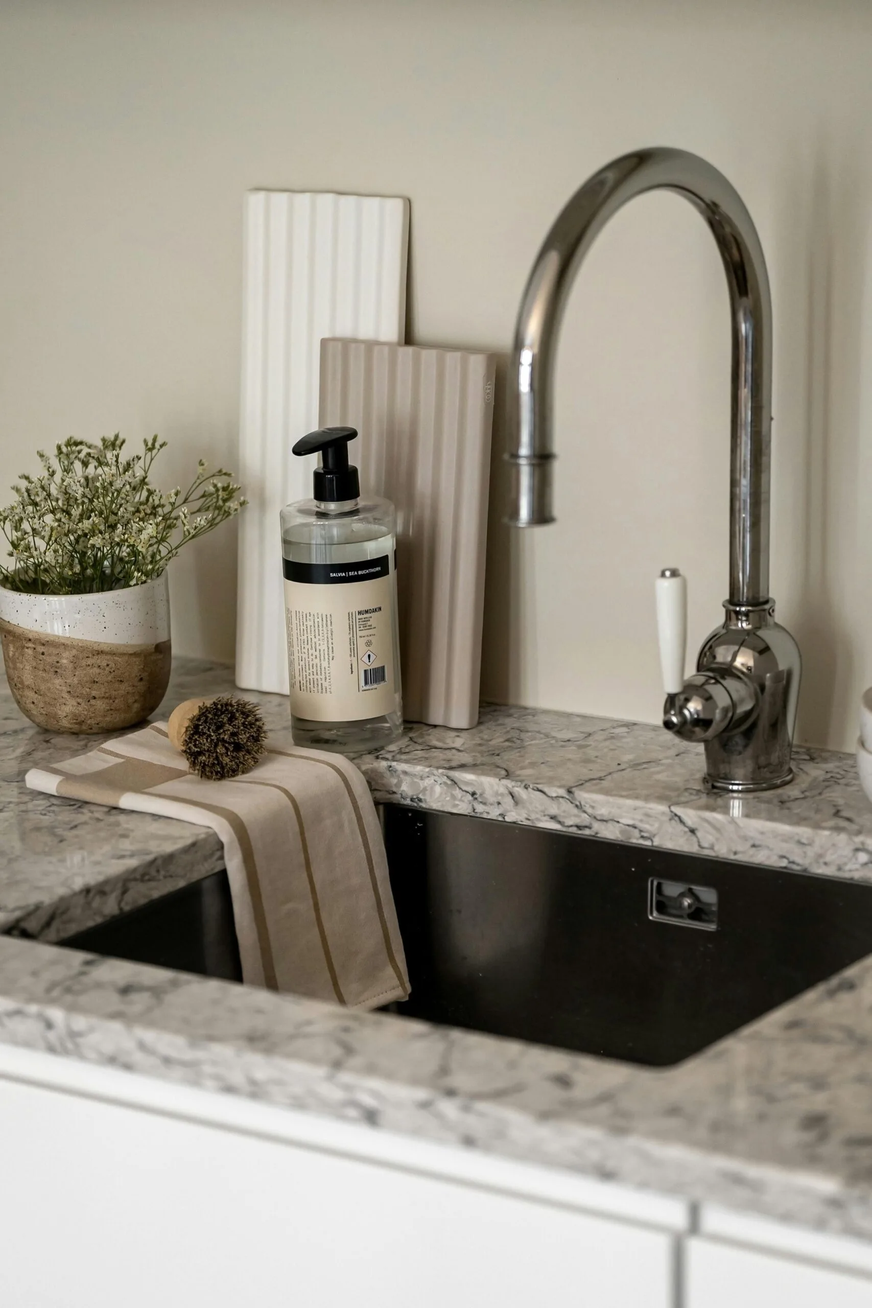Modern kitchen sink with classic tapware, potential splashback tile options leaning against a wall and a natural stone benchtop.