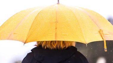 A bright yellow umbrella stands out and offers shelter from the rain.
